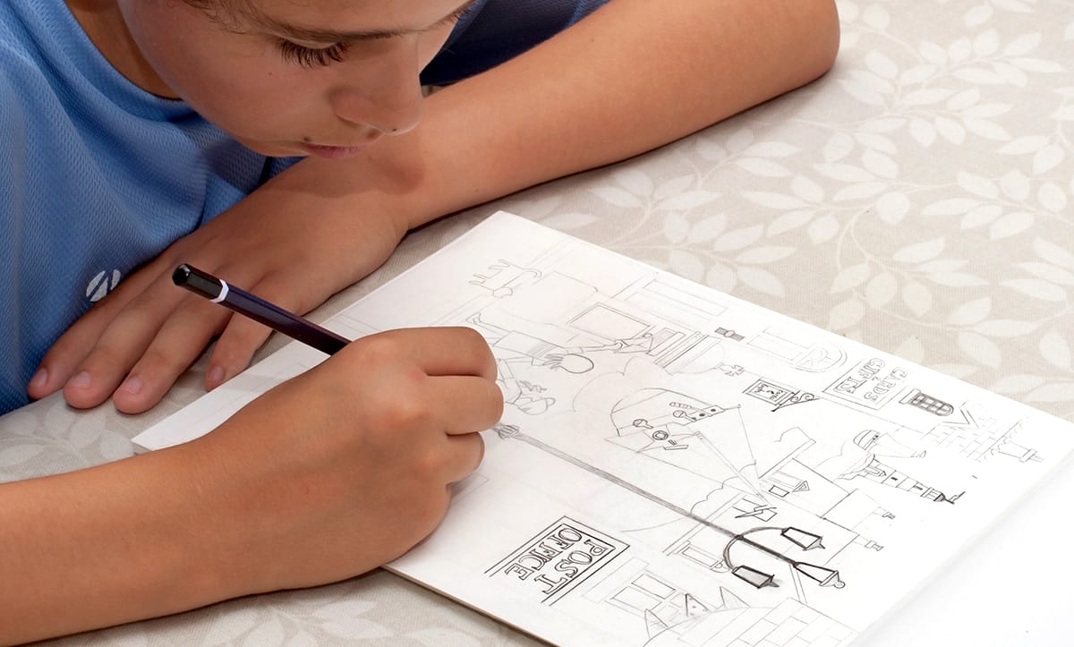 A teenage boy drawing a picture of a seaside town