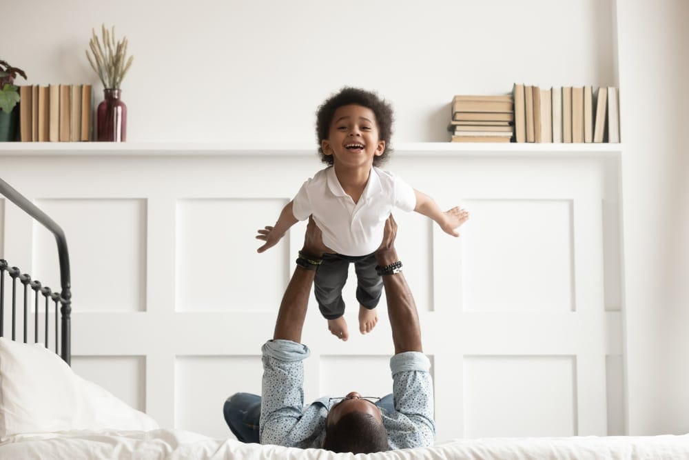 Happy African American Kid Flying In Fathers Arms