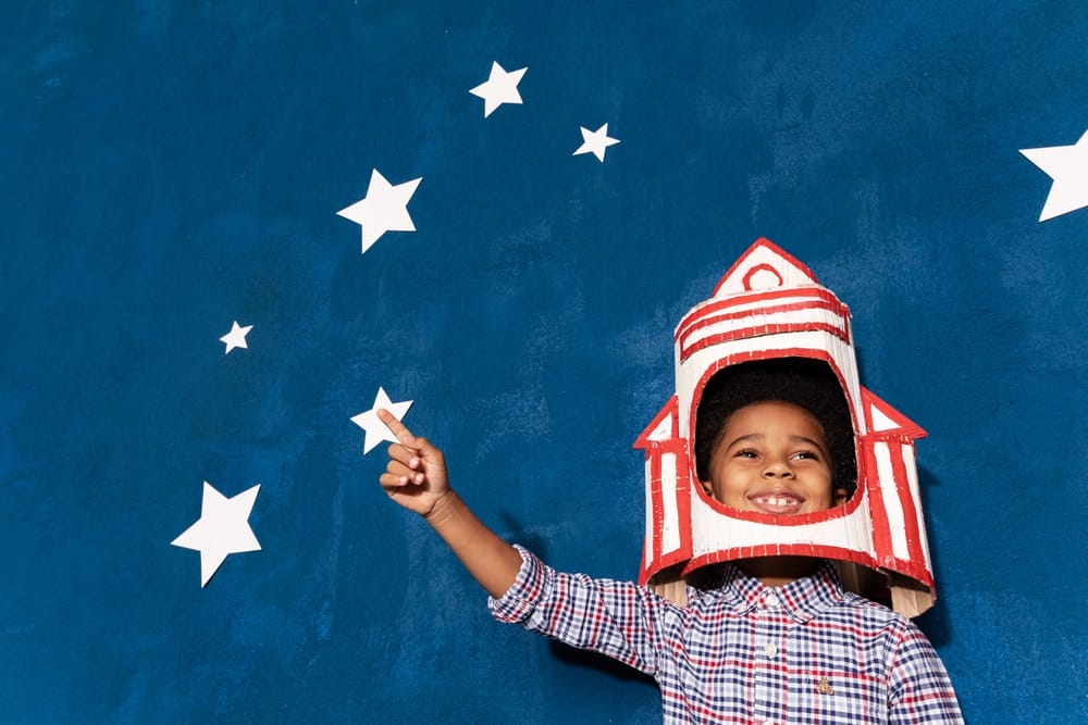 Boy with rocket helmet pointing stars